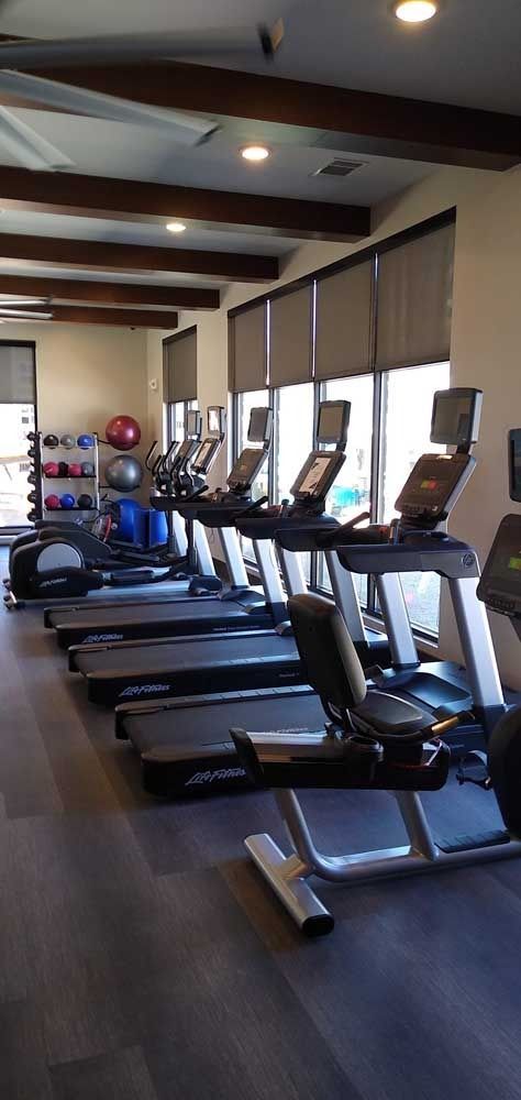 Gym with treadmills and exercise equipment. Windows and wooden beams visible.
