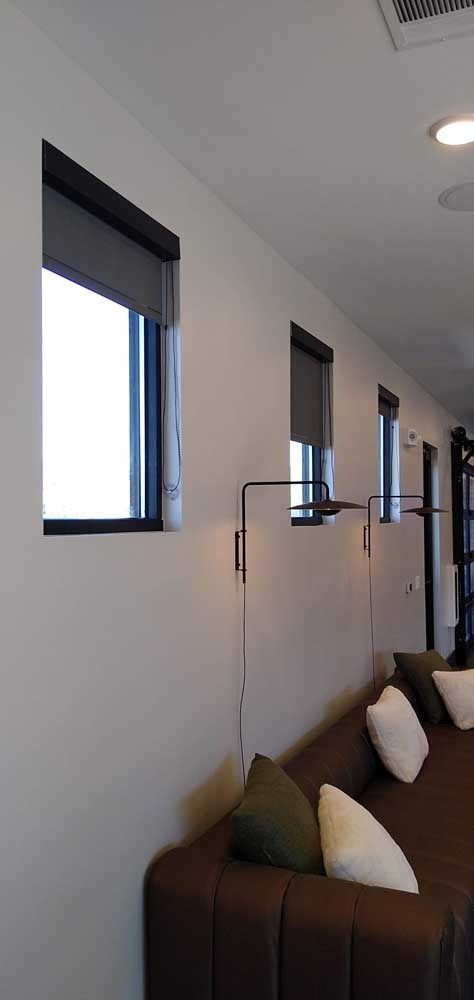 Modern room with windows, a couch, and a wall-mounted light fixture.