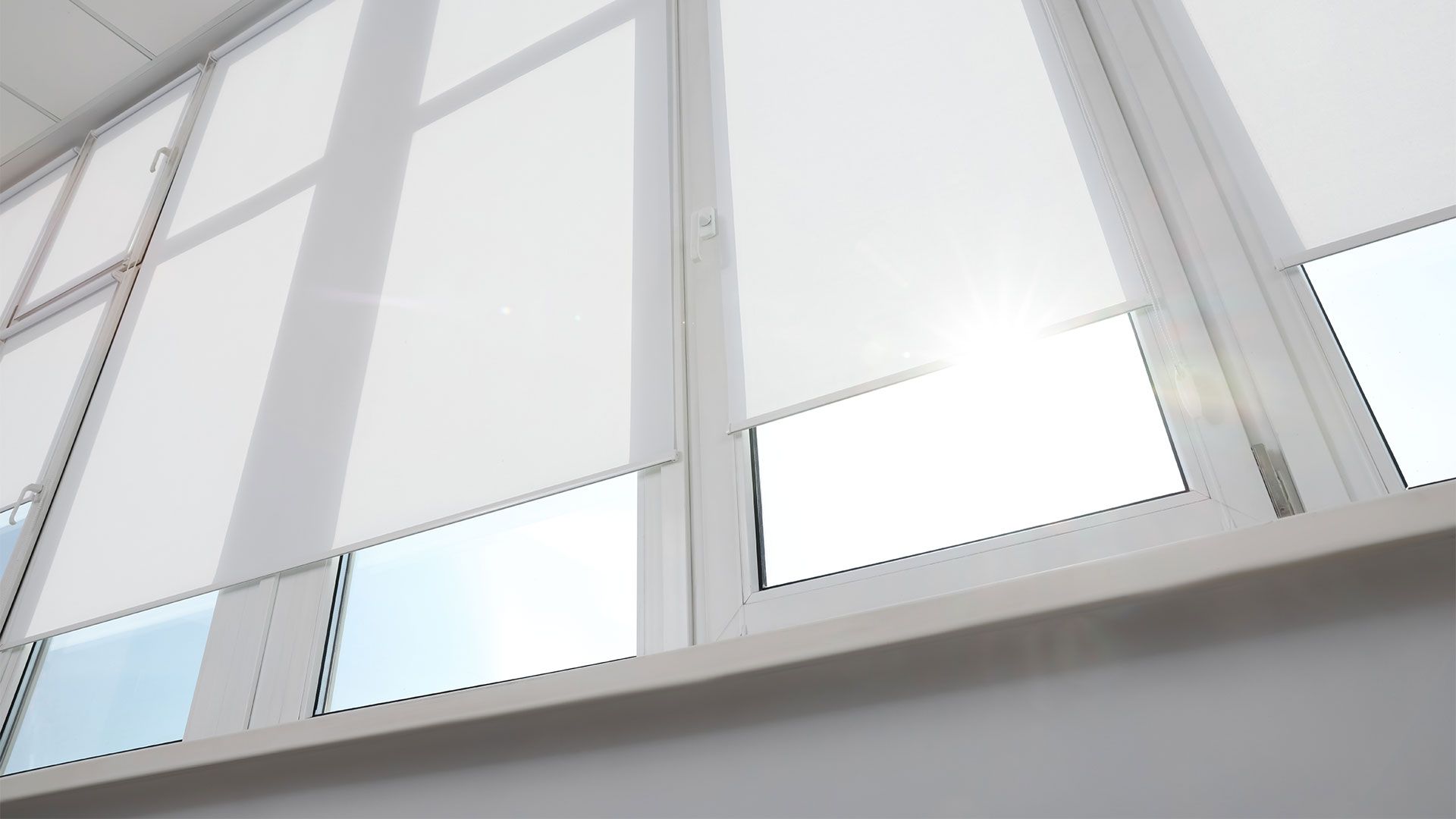 White window with partially lowered blinds; bright sunlight shines through.