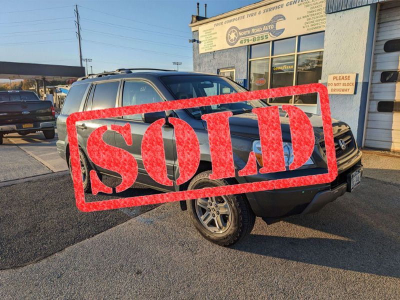 A sold car is parked in front of a garage.