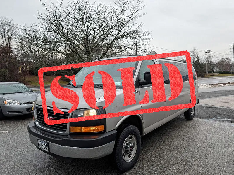 A silver gmc van is parked on the side of the road.