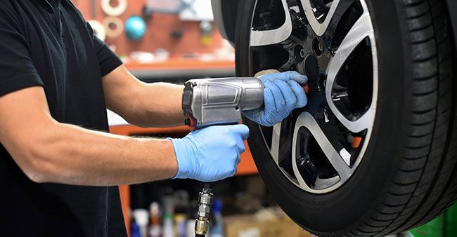 A man is using a wrench to change a tire on a car.