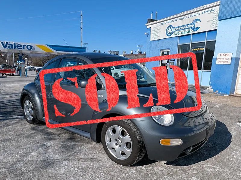 A sold car is parked in front of a garage.