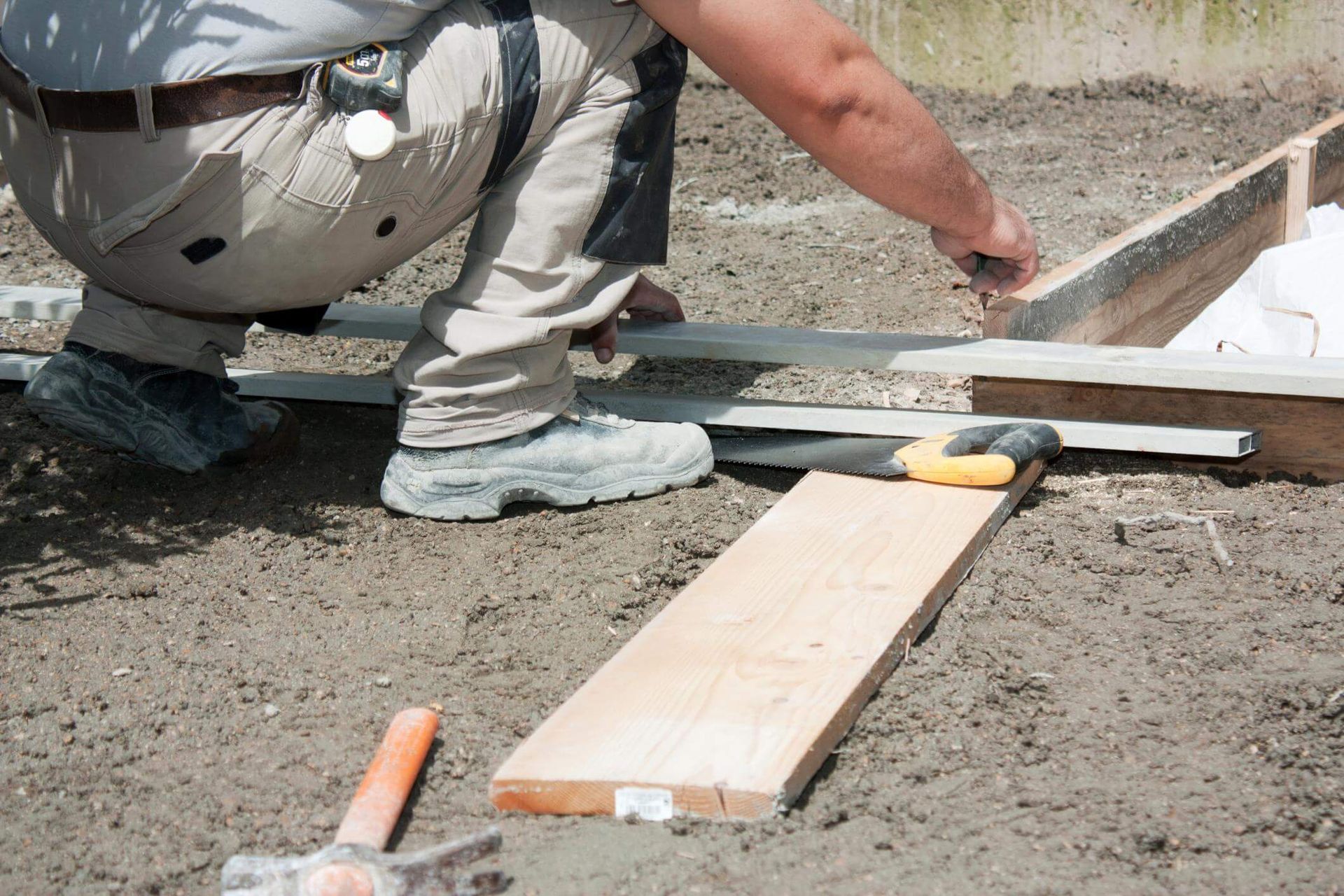 a man kneeling down next to a piece of wood