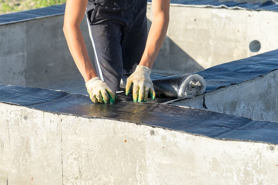a man in black shirt and gloves working on a piece of metal