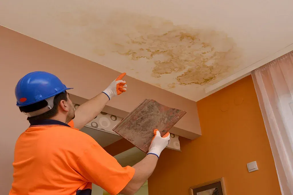 A man is working on a ceiling in a living room.