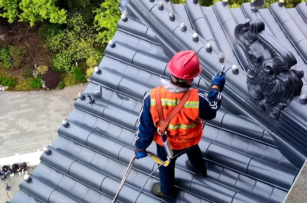 A man is standing on top of a roof holding a rope.