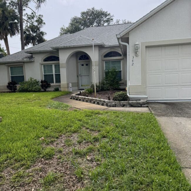 A white house with a gray roof and a white garage door