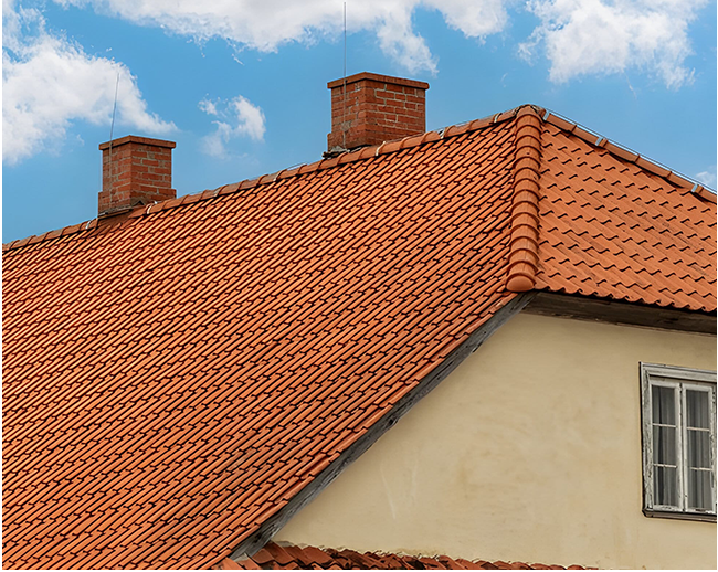 A house with a red tiled roof and chimneys on top of it.