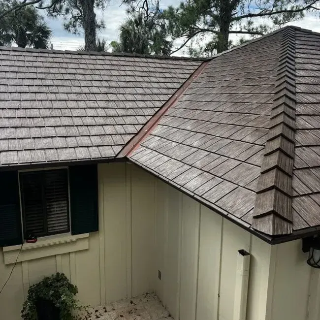 A white house with a wooden roof and blue shutters.