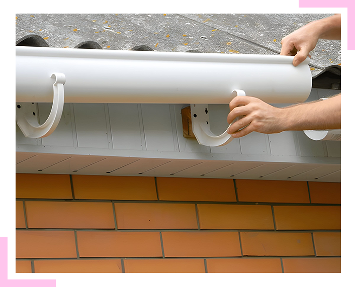 A person is installing a gutter on a brick wall.