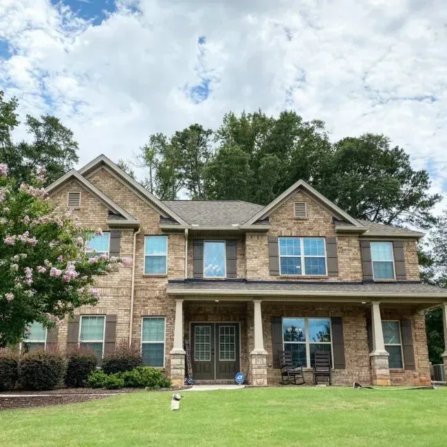 A large brick house with a large lawn in front of it