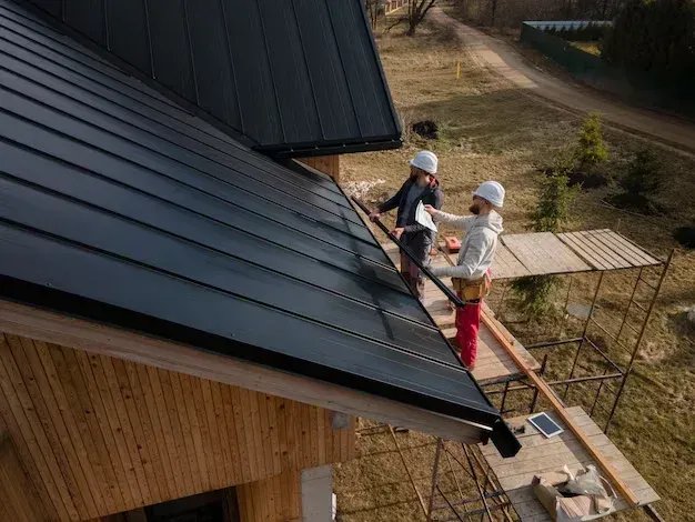 A couple of men are working on the roof of a house.
