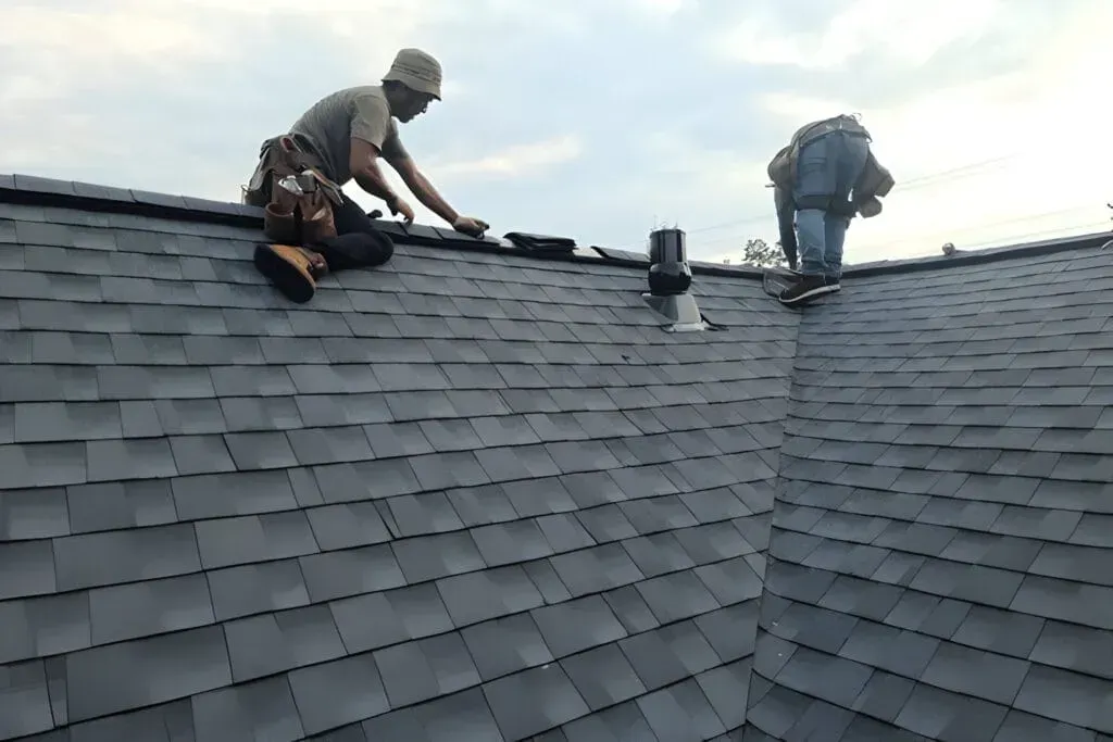 Two men are working on the roof of a house.