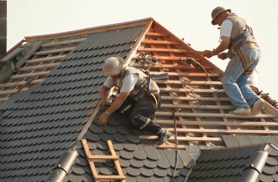 Two men are working on the roof of a house