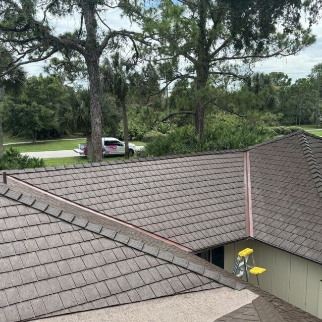 An aerial view of a house with a roof and trees in the background.