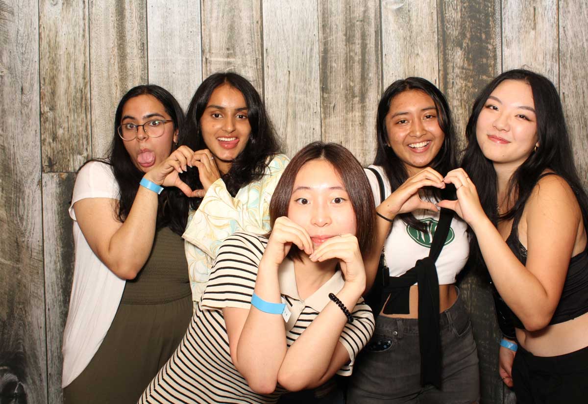 A group of young women are making a heart shape with their hands.