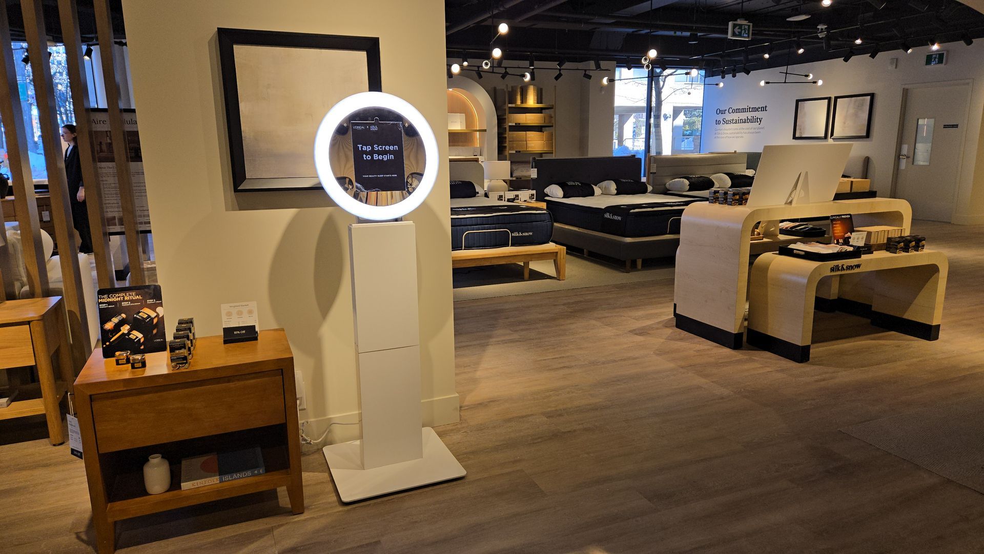Interior of a store with a photo booth, furniture displays, and wooden flooring.