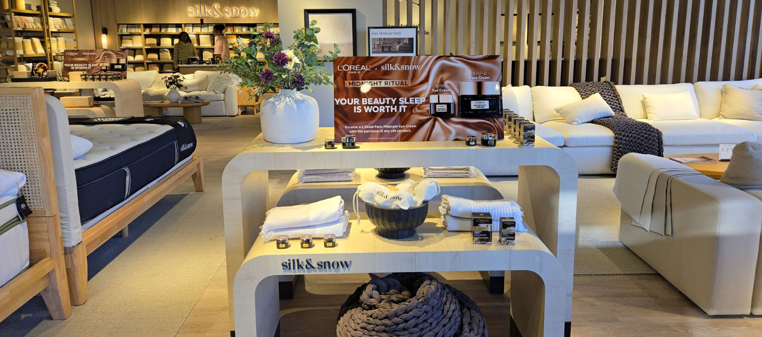 Interior of a furniture store featuring a bed, sofa, and display table with decorative items.