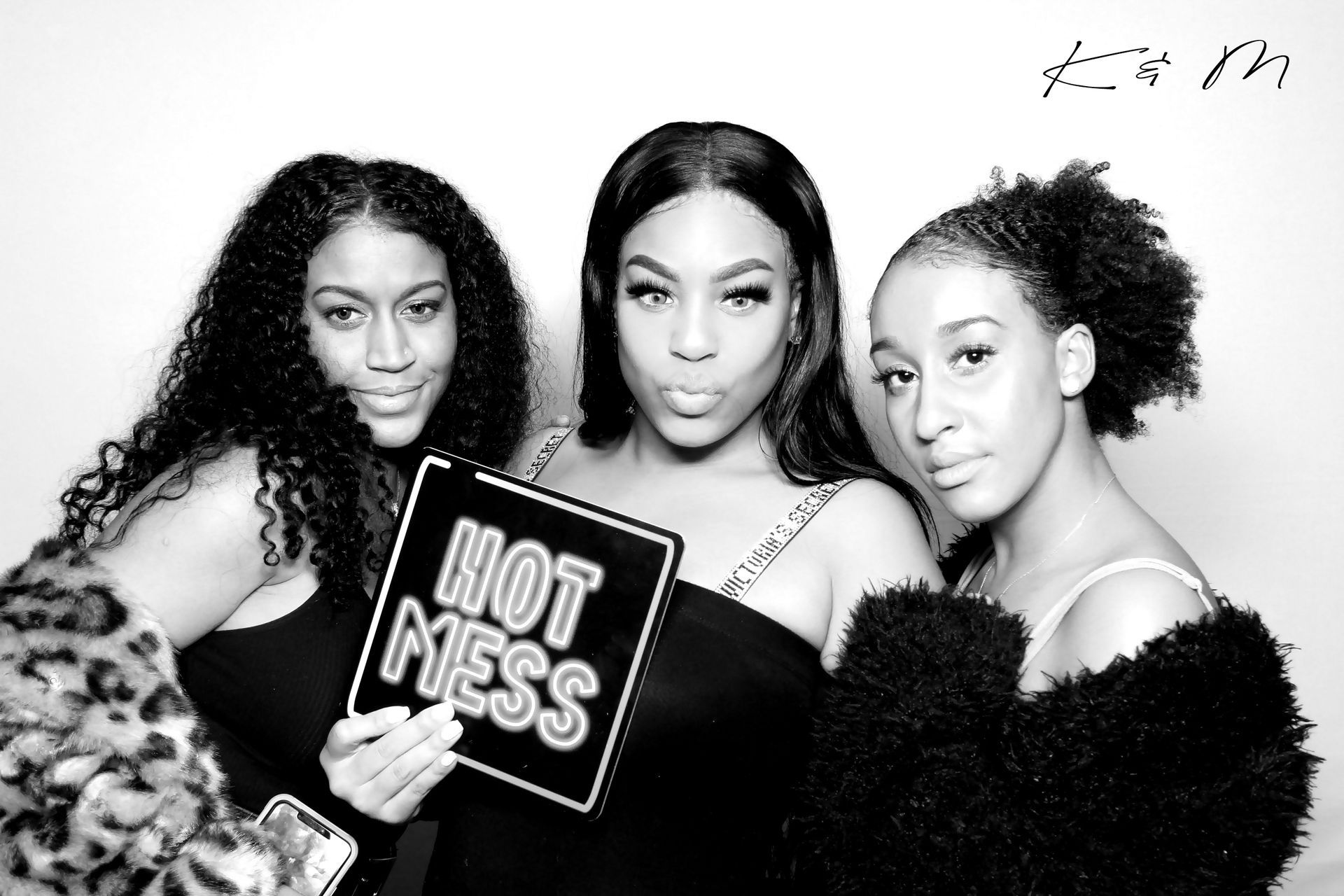 Three people pose for a photo booth. One holds a