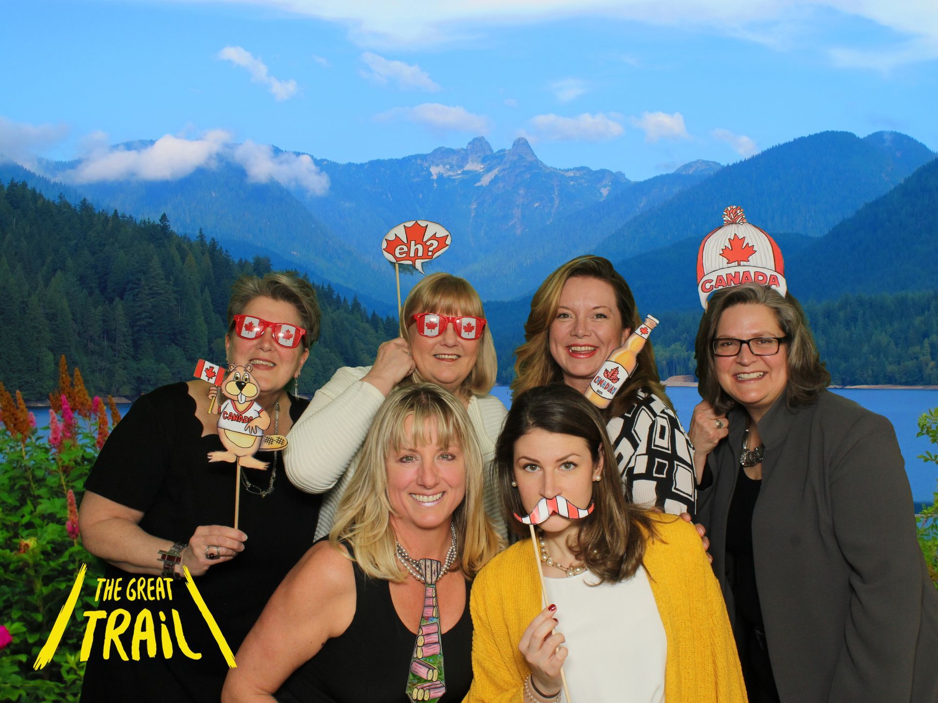 A group of women are posing for a picture with mountains in the background using a greenscreen background of the Great Canadian Trail.  Images provided by LOL Photo Booth GTA.