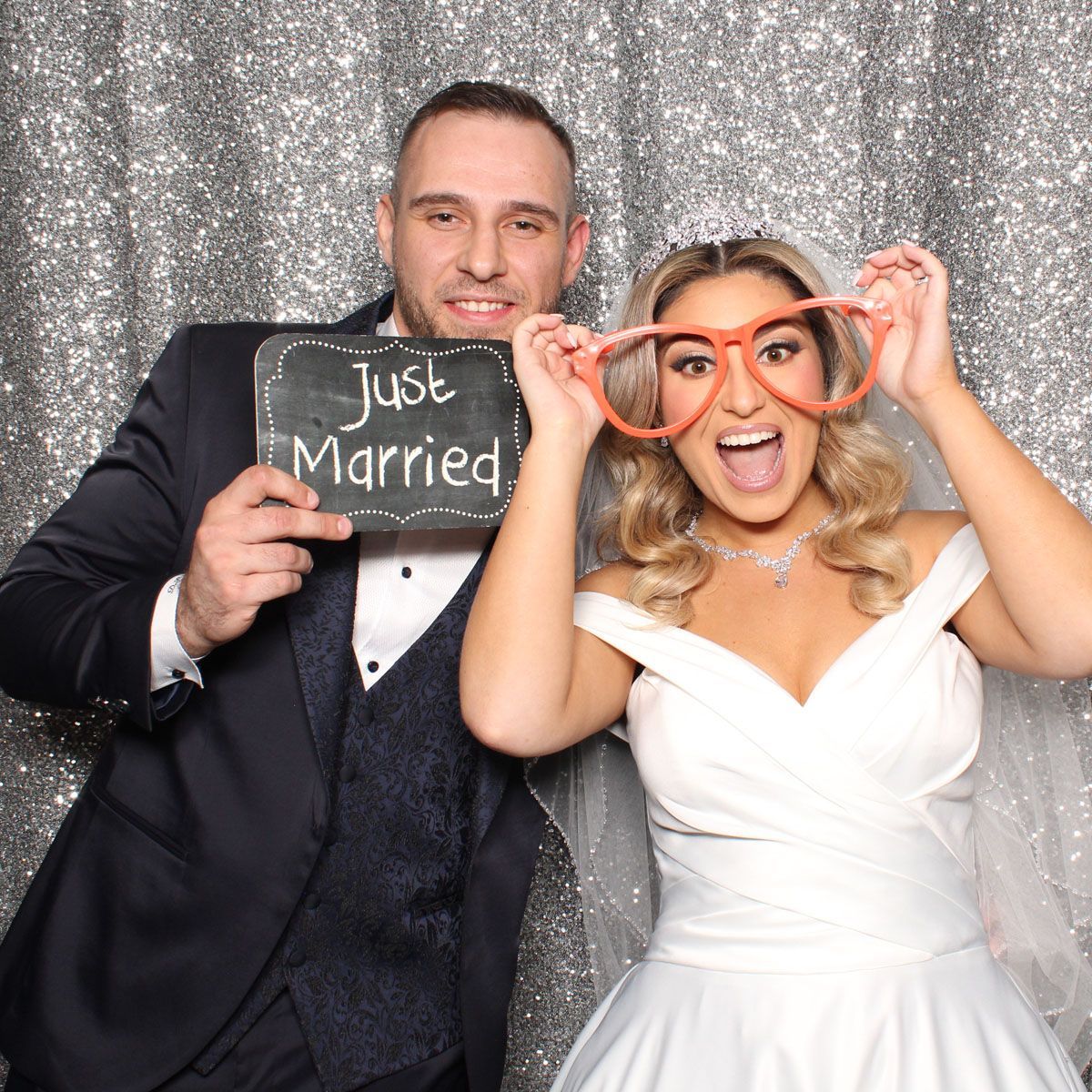 Photo booth wedding photo of bride and groom holding a sign that says 