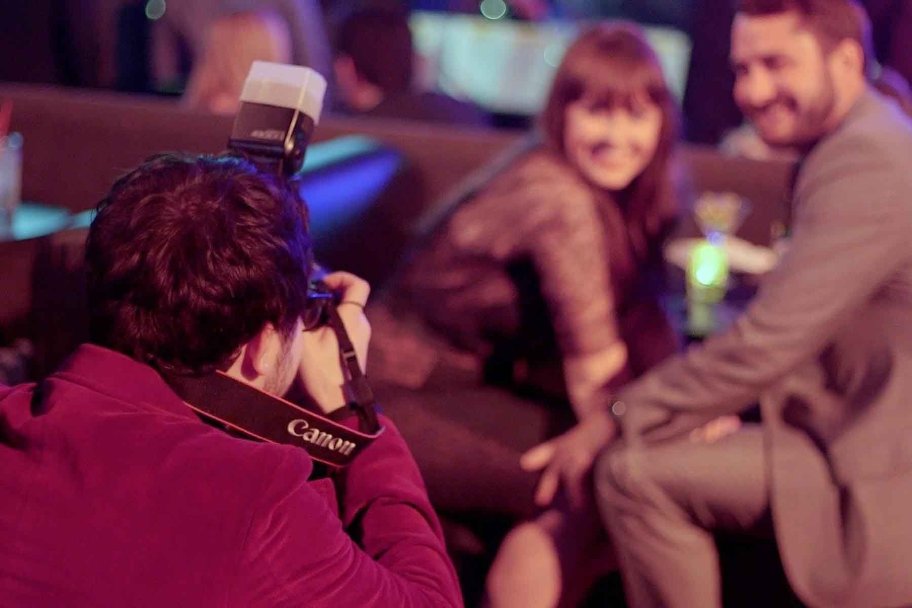 A man is taking a picture of a man and woman sitting on a couch.