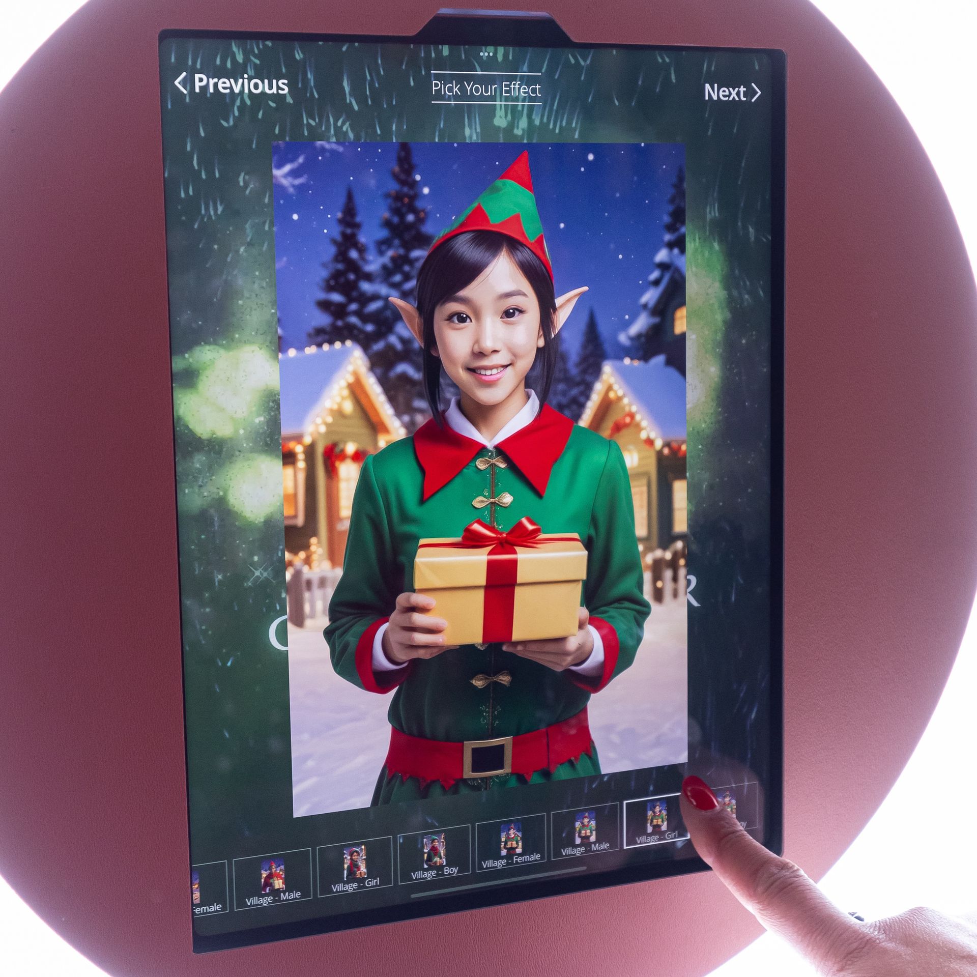Person in elf costume holding gift on a touch screen. Christmas scene background. Finger touching screen.