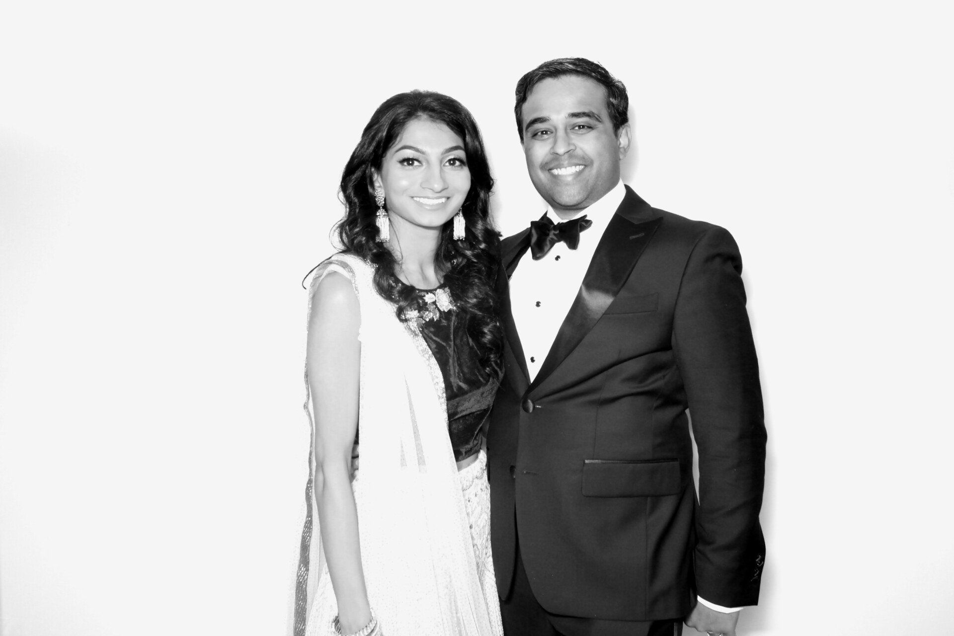 A man in a tuxedo and a woman in a white dress are posing for a picture.