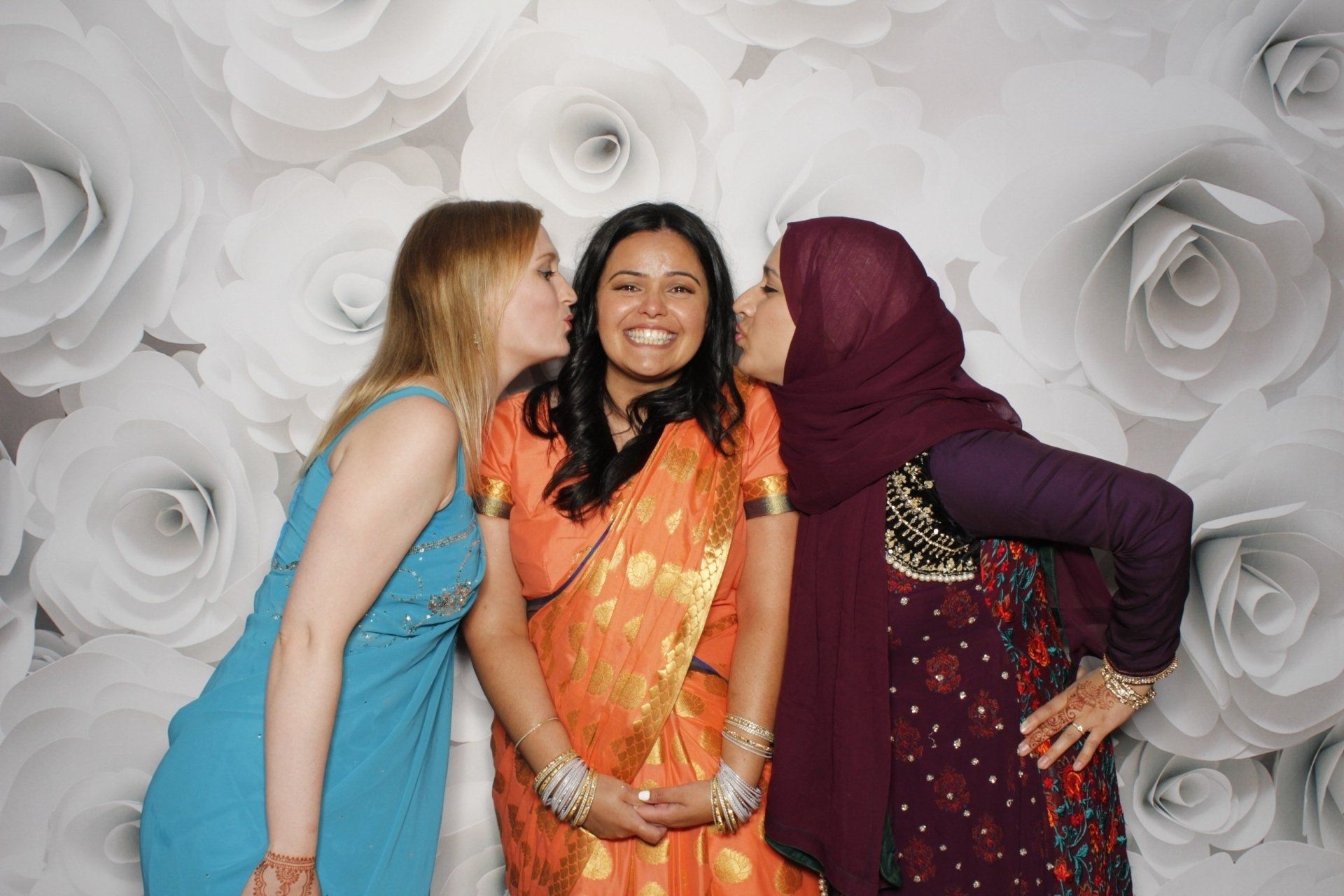 Three women are posing for a picture and one of them is kissing another woman on the cheek.