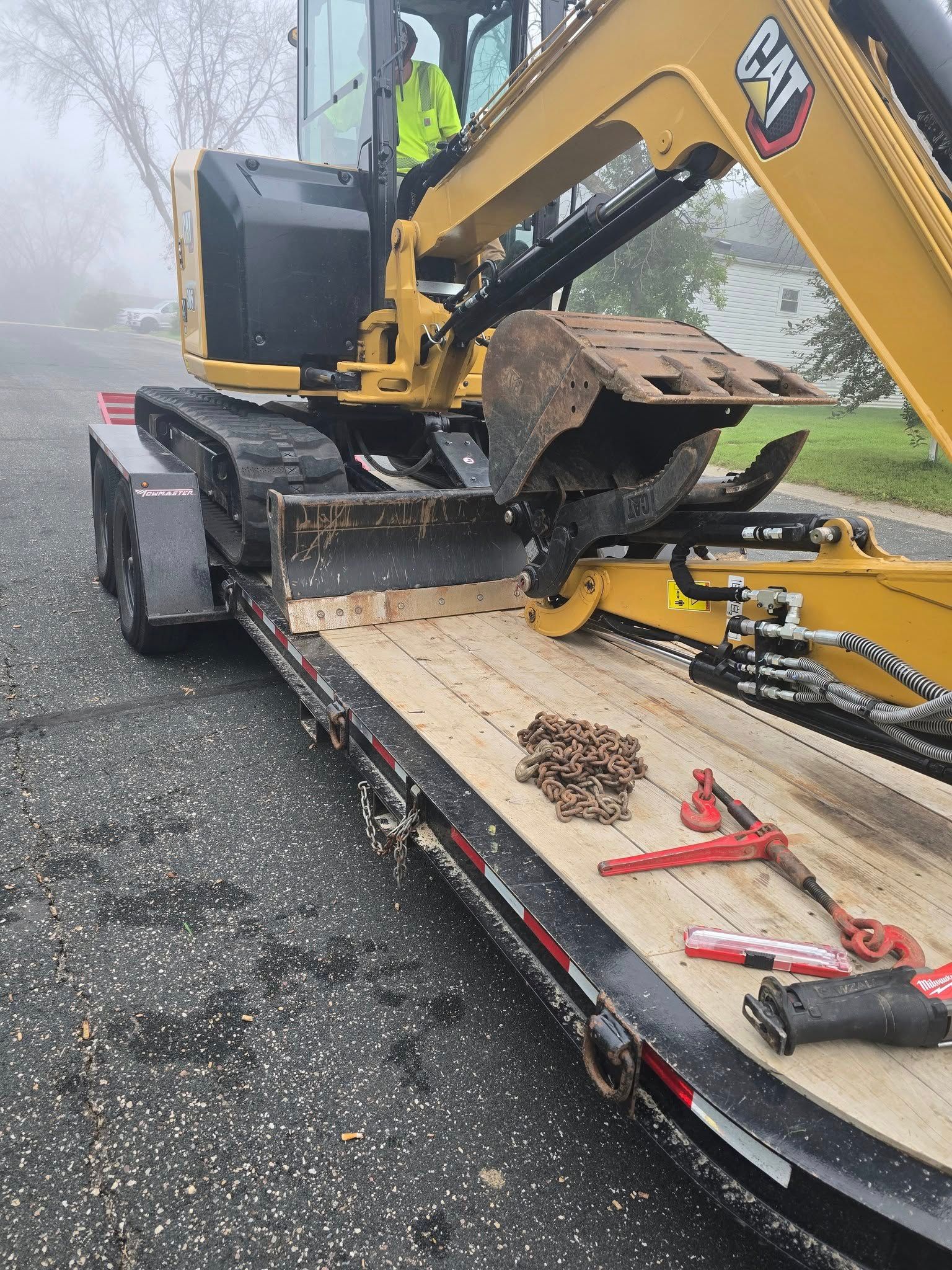 Yellow excavator on a trailer parked on a road.