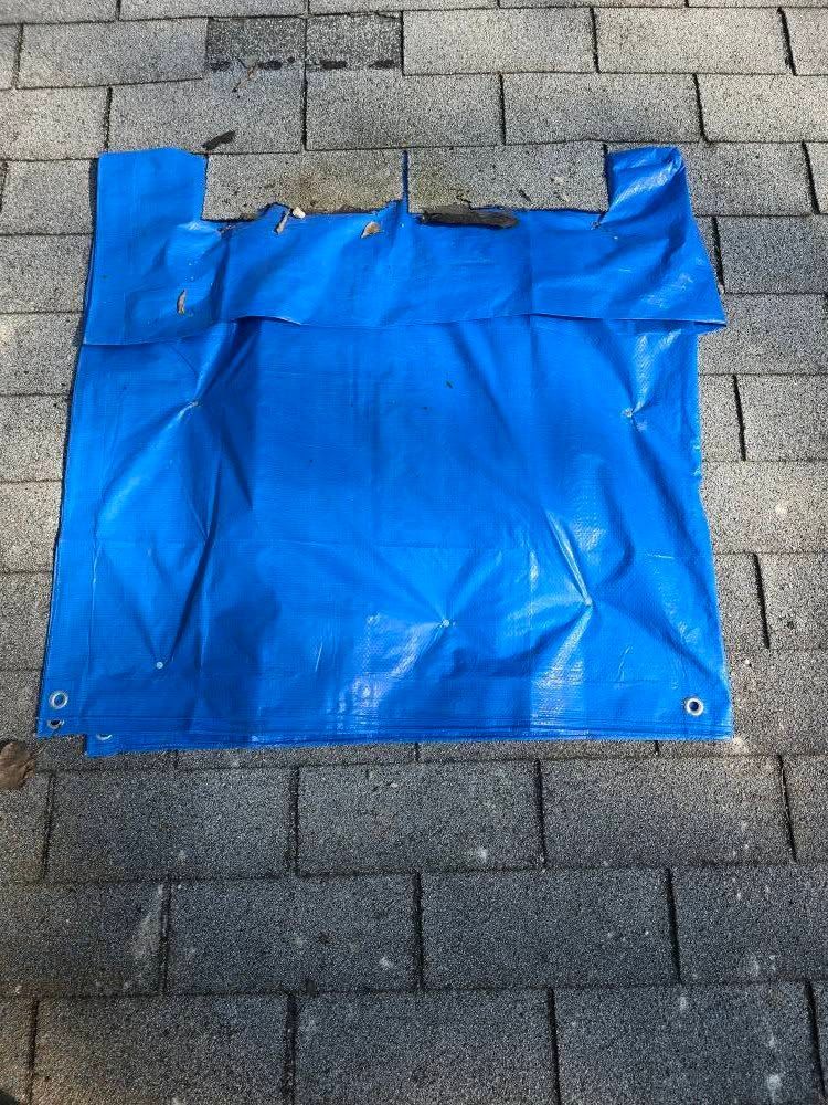 Blue tarp on a brick surface with folded edges and eyelets.