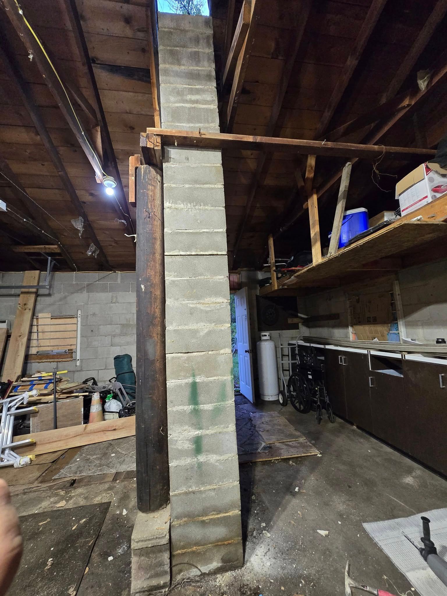Concrete block column supporting a wooden beam in a basement.