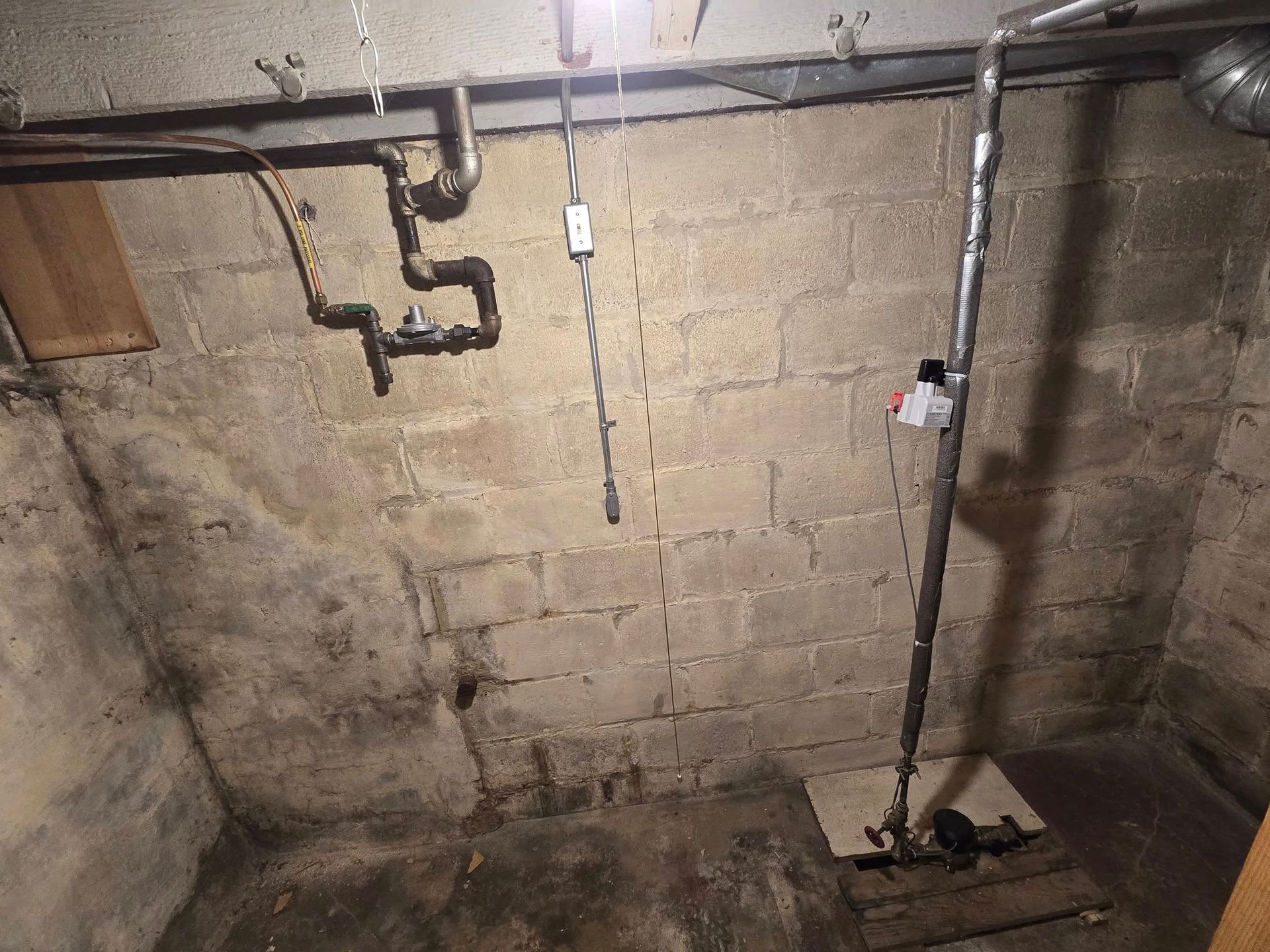 Concrete basement with pipes and plumbing.