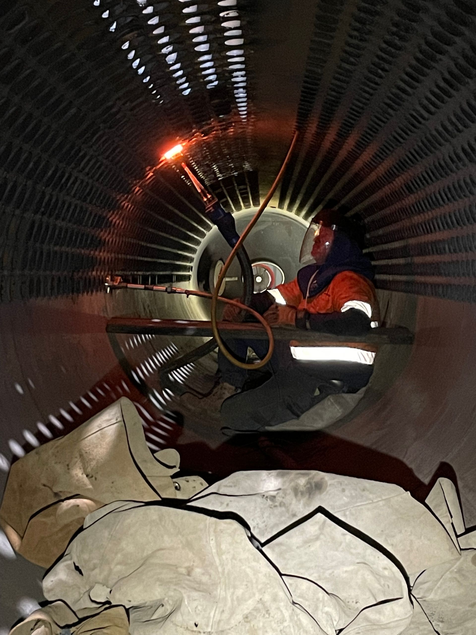 A red fan is sitting on a wooden bench in a tunnel.