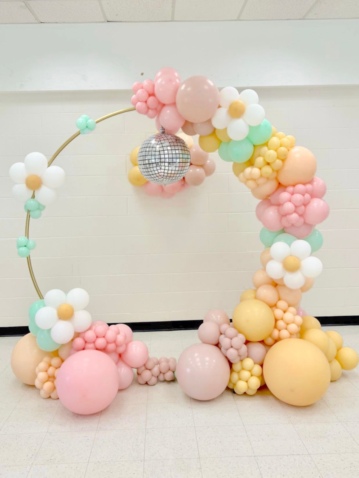 A balloon arch with flowers and balloons in a room.