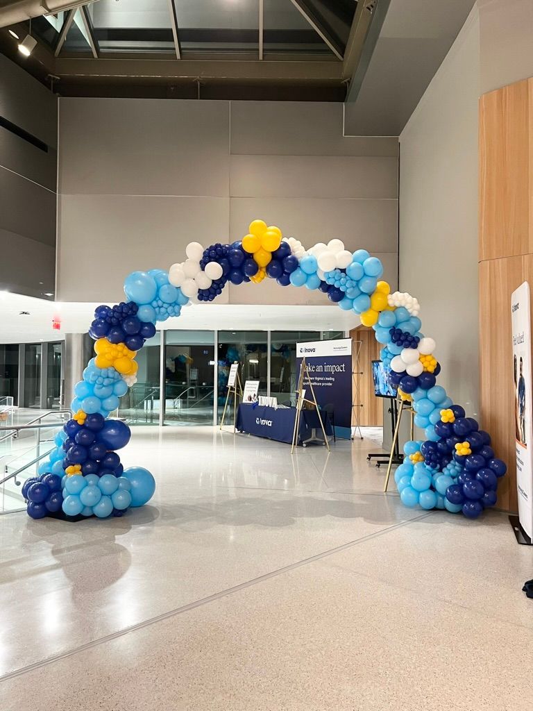 A large arch made of blue and yellow balloons in a lobby.