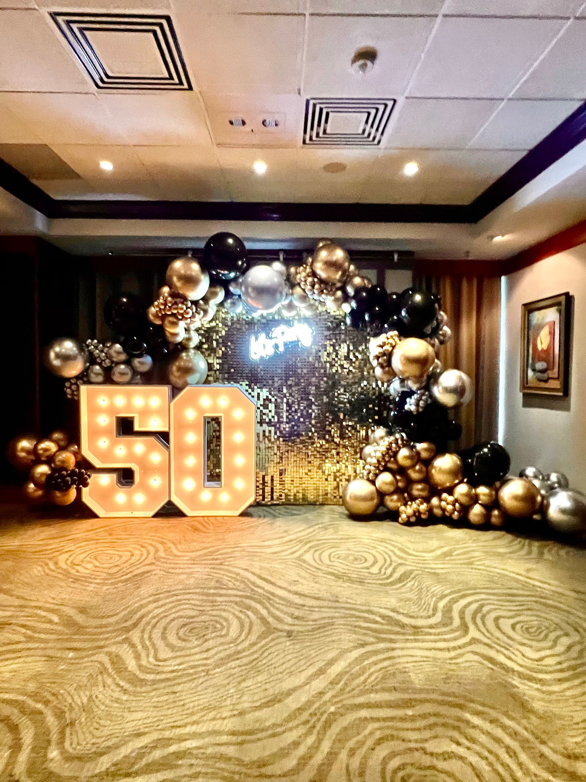 A room decorated with balloons and lights for a 50th birthday.