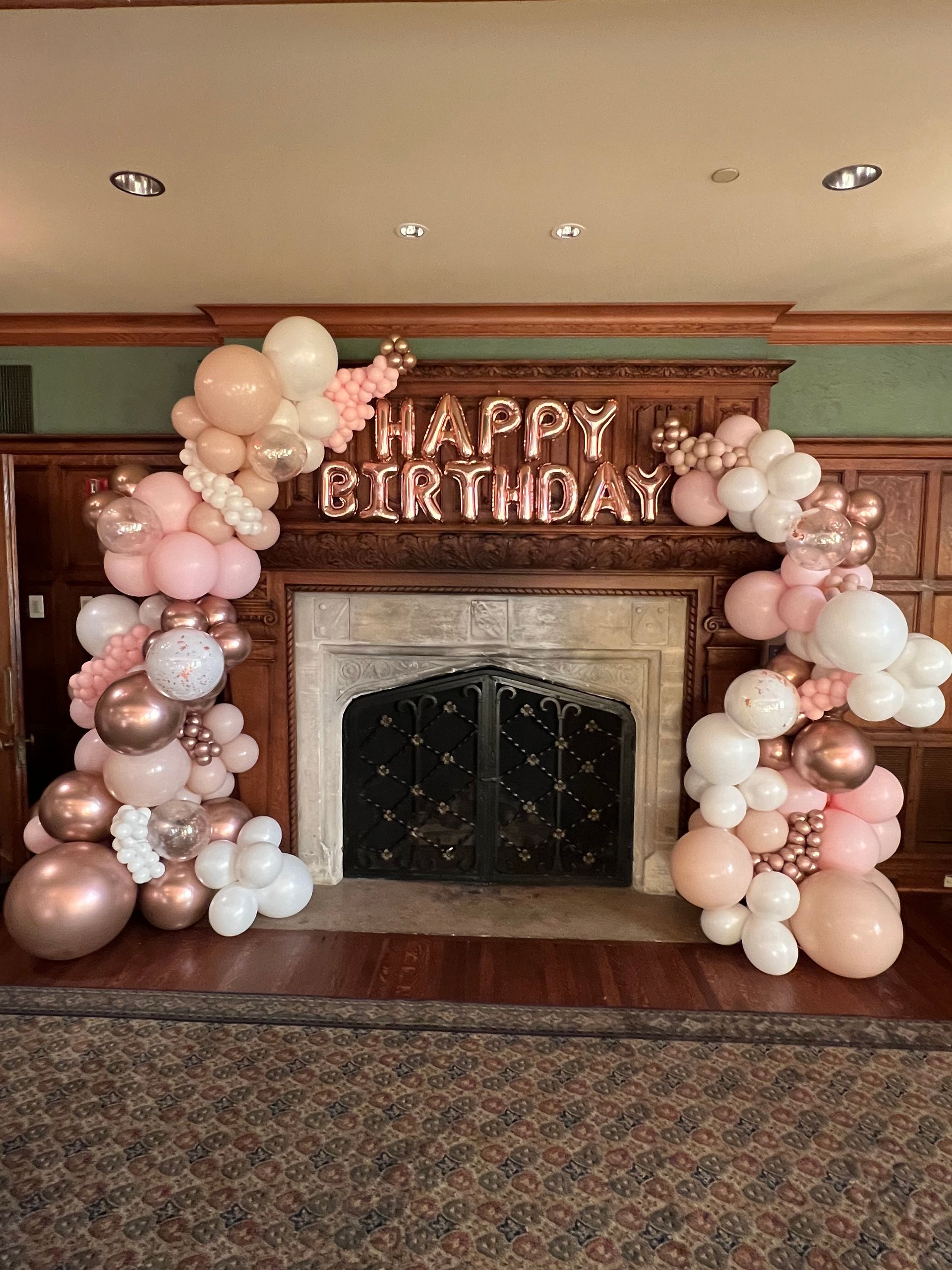 A fireplace decorated with balloons and a sign that says `` happy birthday ''.