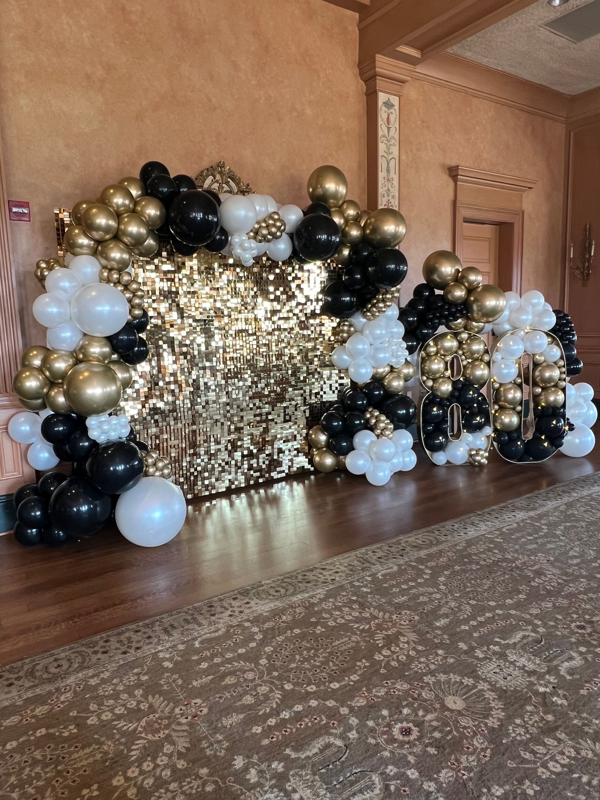 A room filled with black , gold and white balloons.