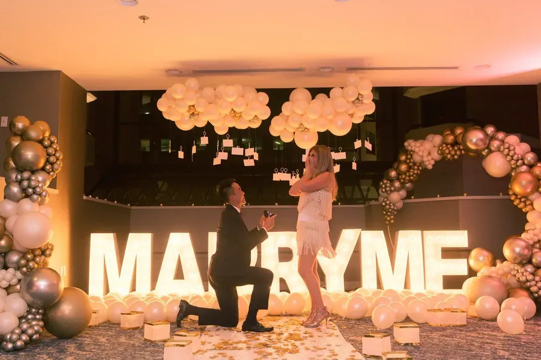 A man is kneeling down in front of a sign that says marry me.