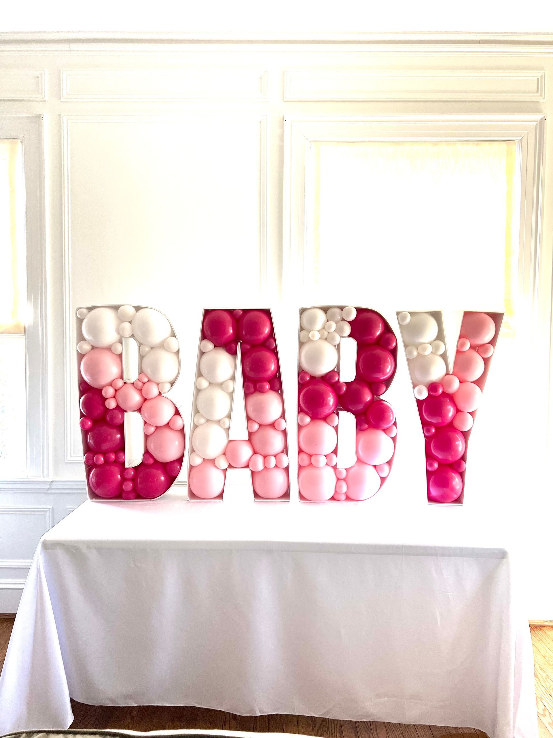 The word baby is made out of pink and white balloons