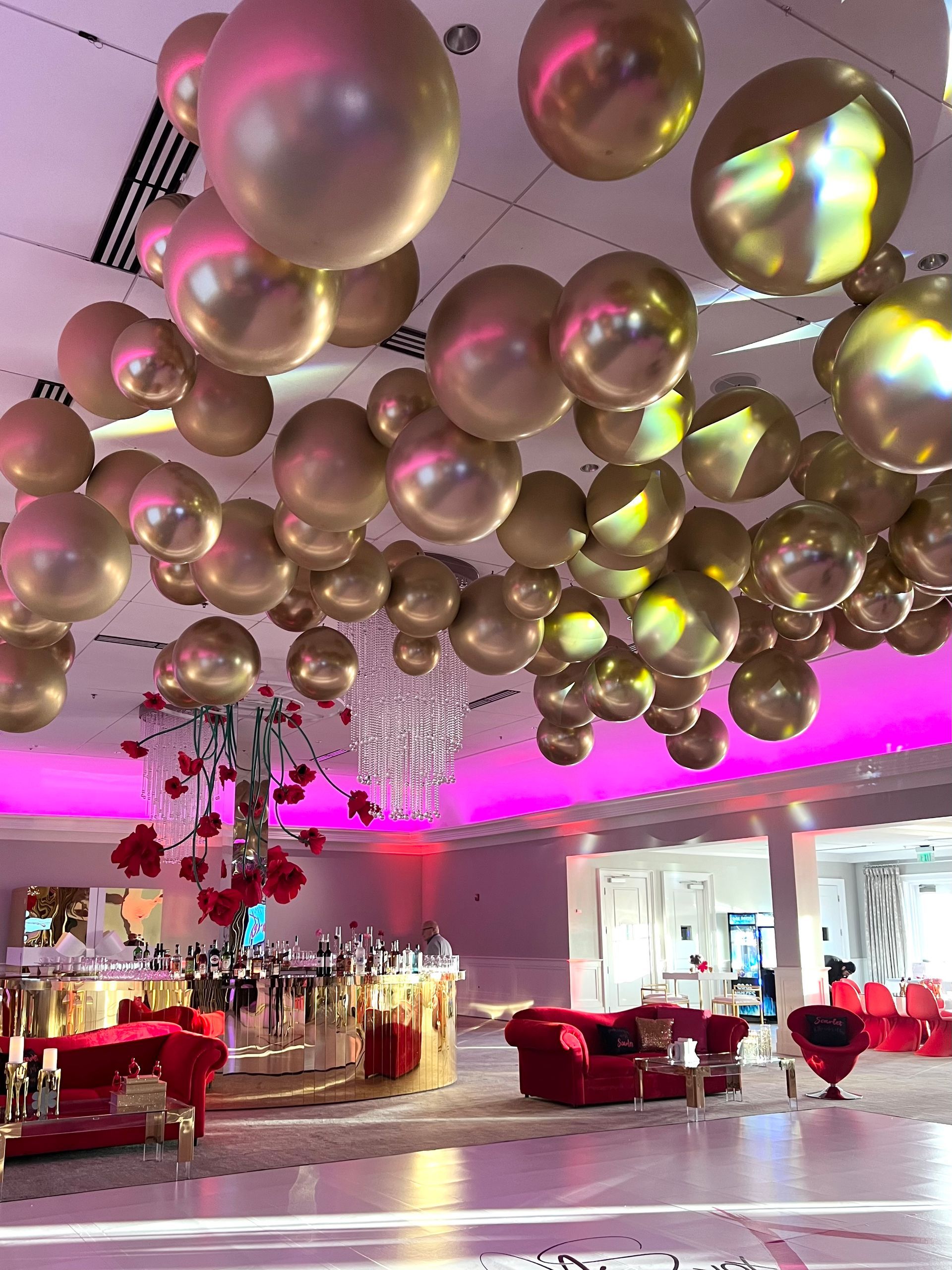 A bunch of gold balloons are hanging from the ceiling of a room.