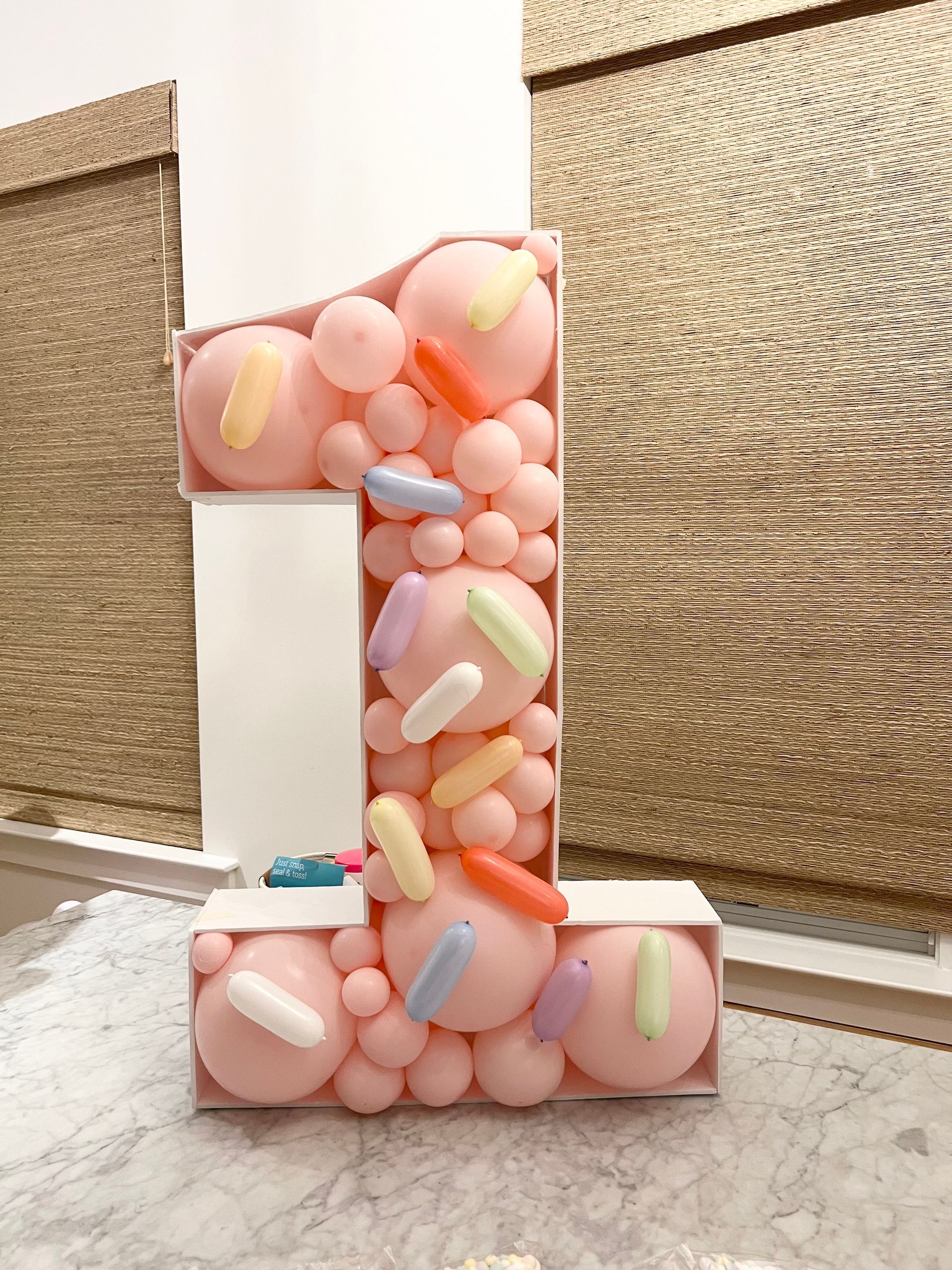 A number 1 made of pink balloons and sprinkles
