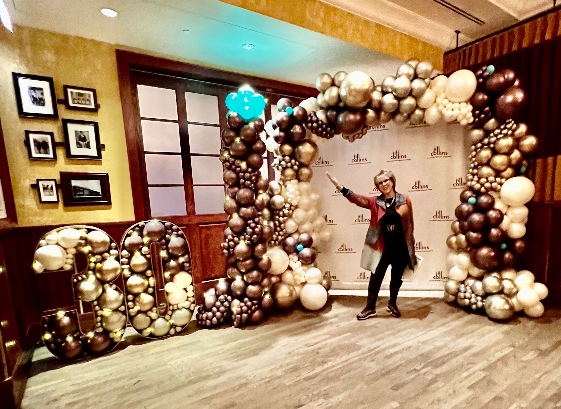 A woman is standing in front of a wall of balloons.