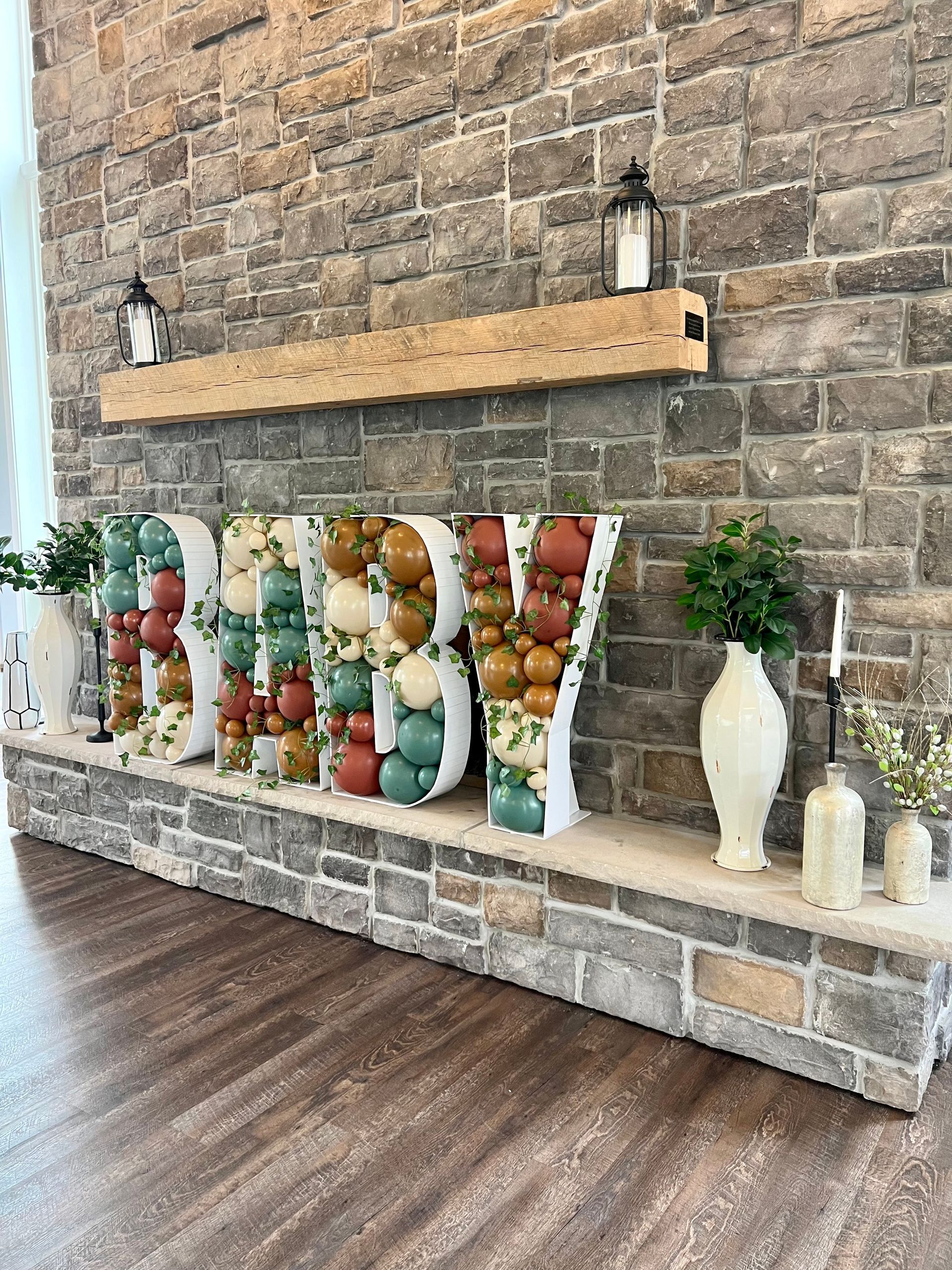 A fireplace with balloons shaped like the word baby on it.