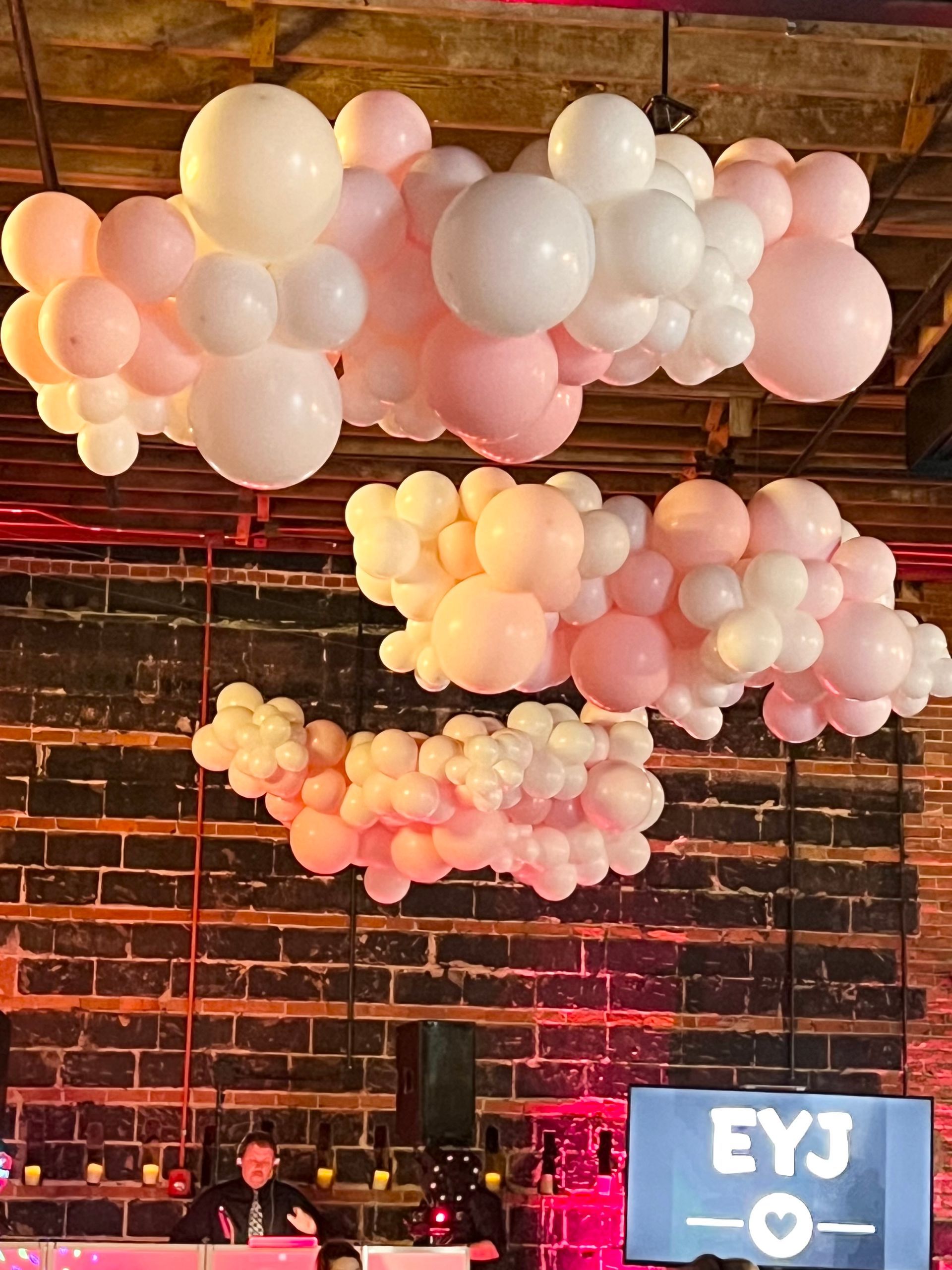 A bunch of pink and white balloons hanging from the ceiling of a room.