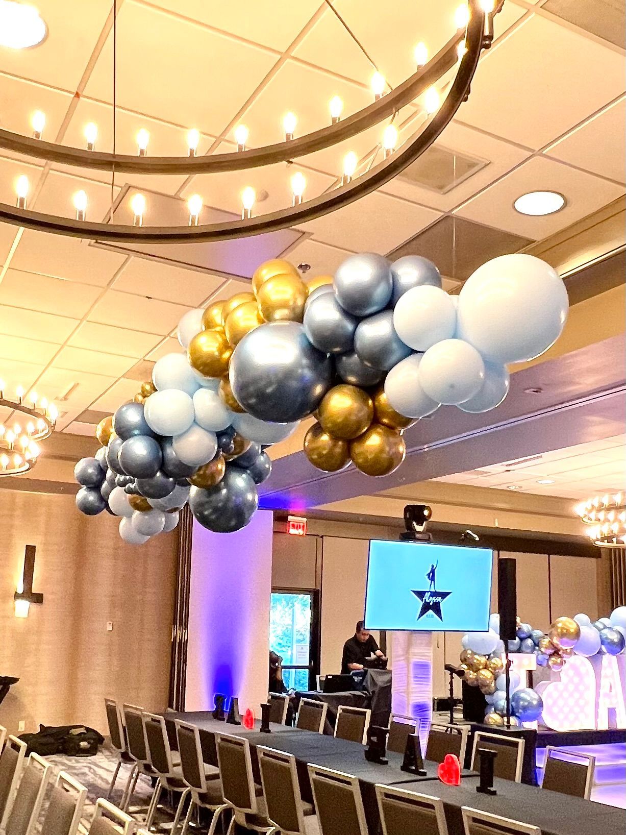 A room with a long table and chairs and balloons hanging from the ceiling.