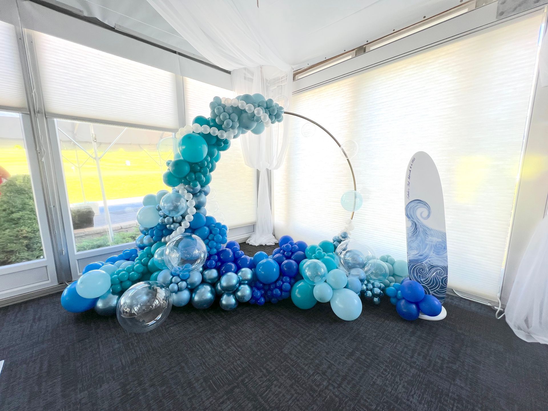 A room filled with blue balloons and a surfboard.