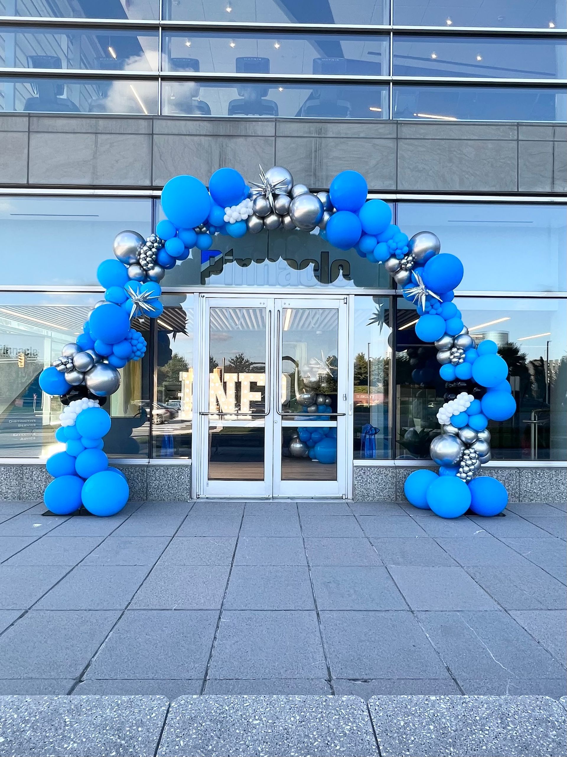 A blue and silver balloon arch is in front of a building.